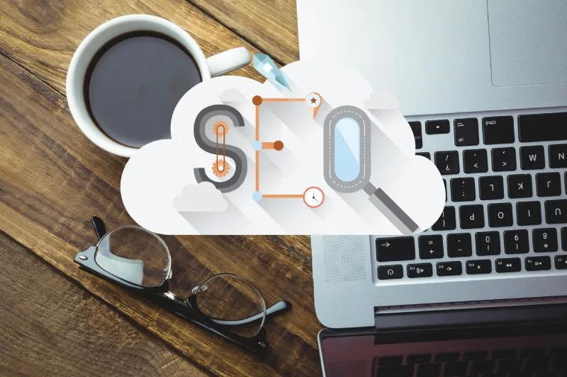 Coffee and laptop with SEO cloud graphic showing optimization tools.