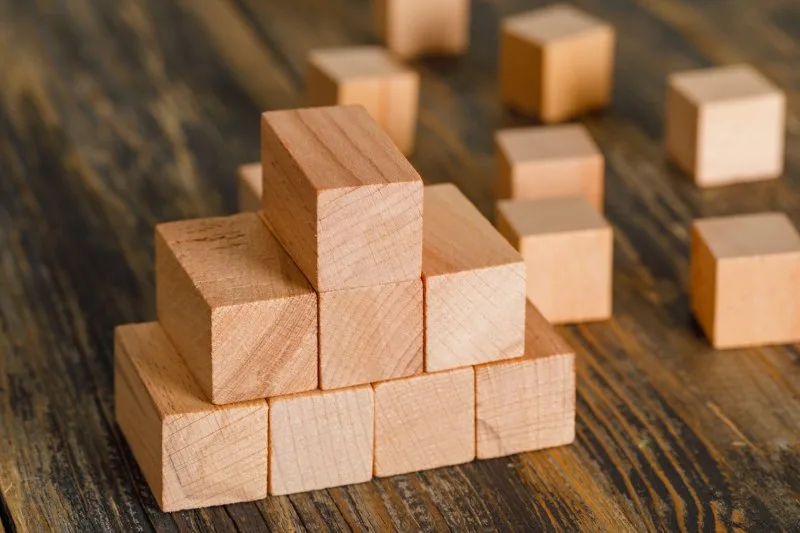 Wooden cubes stacked in a pyramid shape on a wooden table symbolizing structured website content hierarchy.