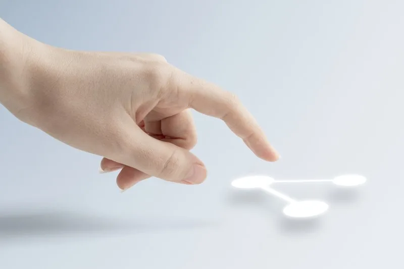 Hand pointing toward a digital data network symbol on screen.