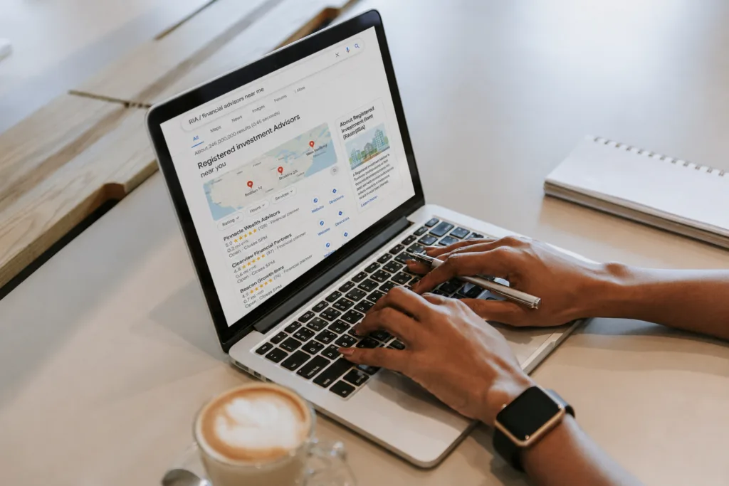 Person using a laptop showing local RIA search results, illustrating the challenge of scaling visibility across multiple markets.