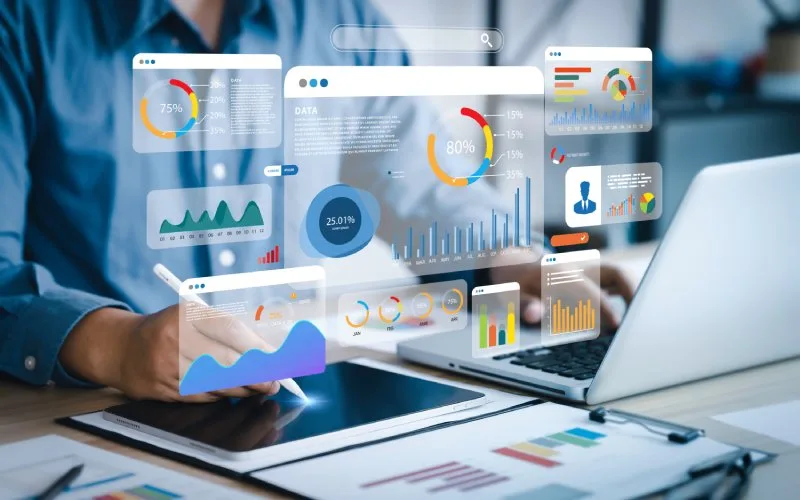Marketer builds GA4 KPI dashboard on tablet and laptop, visualizing engagement, acquisitions, conversions, and revenue trends.