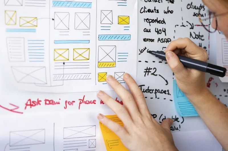 Handwriting notes on website wireframes with boxes and arrows illustrating website content hierarchy planning.