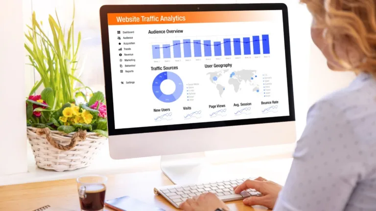 Analyst reviews website traffic analytics on desktop, monitoring audience overview, traffic sources, and user geography KPIs.