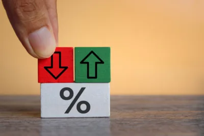 Hand placing a red down arrow block next to green, above percent sign.