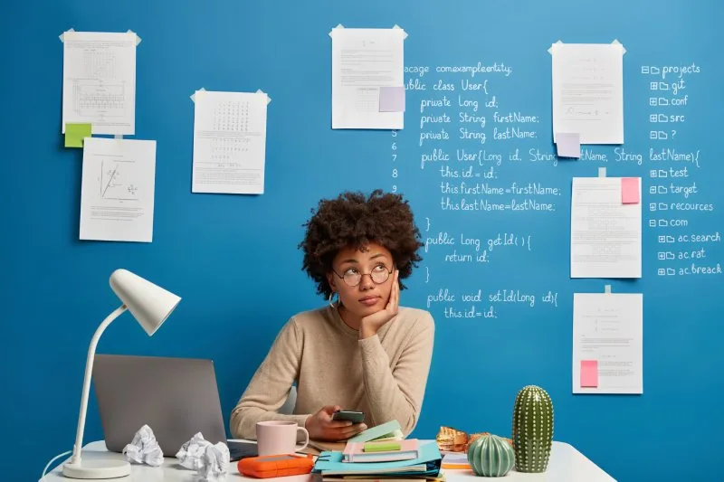Marketer at a desk surrounded by notes and code on a blue wall, planning a topic cluster content structure strategy