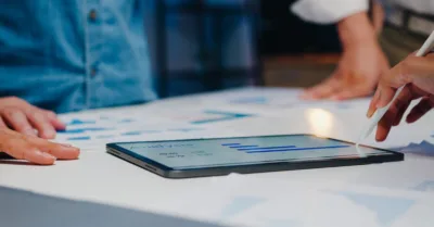 Tablet showing analytics during team meeting about SEO strategy performance.