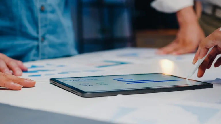 Tablet showing analytics during team meeting about SEO strategy performance.