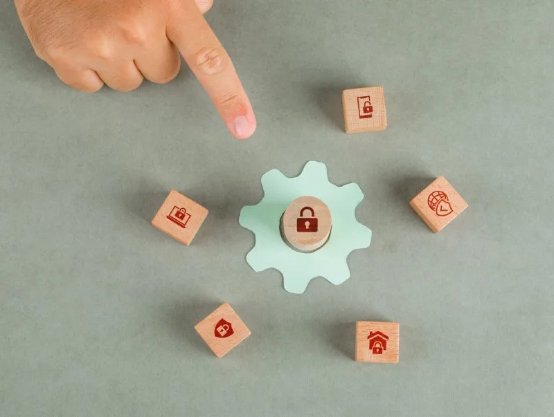 Person pointing to central gear surrounded by wooden blocks with icons representing website content hierarchy.