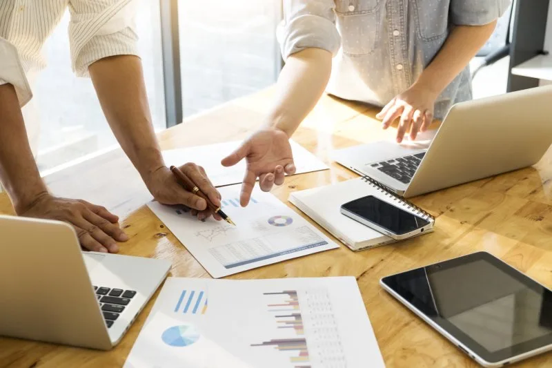 Team analyzing digital marketing performance metrics and data visualization on a laptop during consultation.