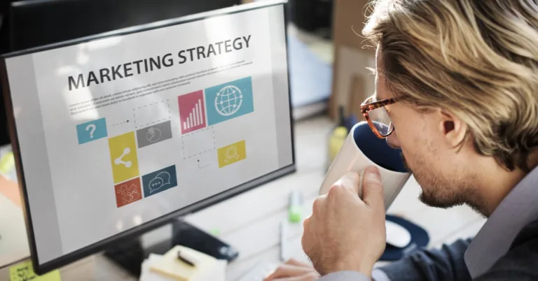 A professional sipping coffee while reviewing a marketing strategy on screen.