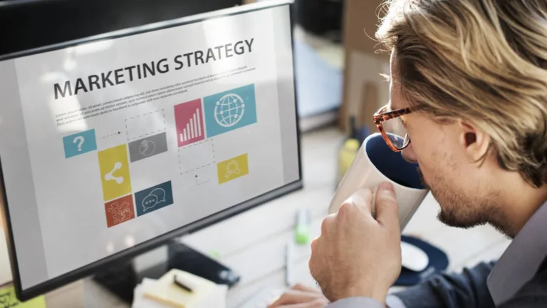 A professional sipping coffee while reviewing a marketing strategy on screen.