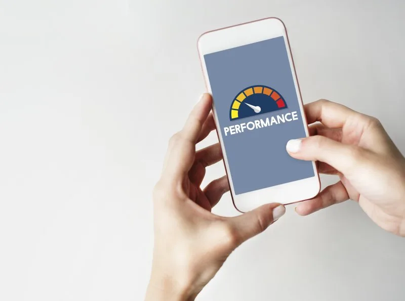 Hands holding a smartphone displaying a mobile site performance speed gauge