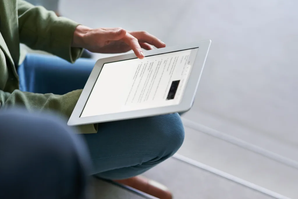 Person sitting and scrolling through a document on a tablet.