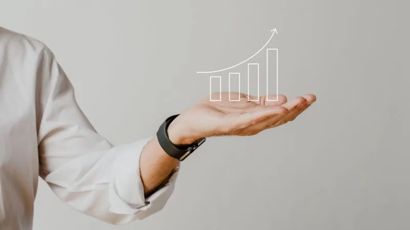 View of a person's shoulder reaching hand out with a growth chart symbol rising from their hand