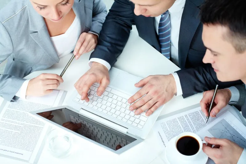 Business team reviewing laptop data and reports together, planning a comprehensive SEO AI agent strategy.