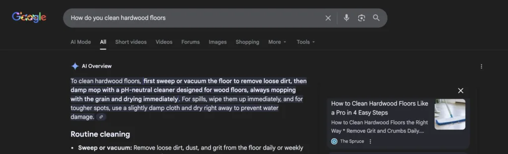Google search results page in dark mode showing how The Spuce pops up in an AI overview with the search term "How do you clean hardwood floors?"