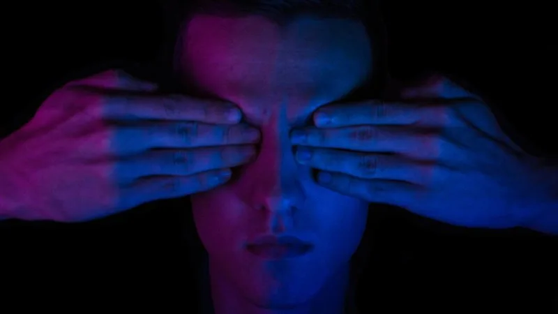 Person covering own eyes against digital spray, symbolizing what’s blocking your AI visibility in content.