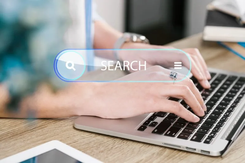 Person typing on a laptop with a search bar overlay, representing AI-driven search and discovery. 