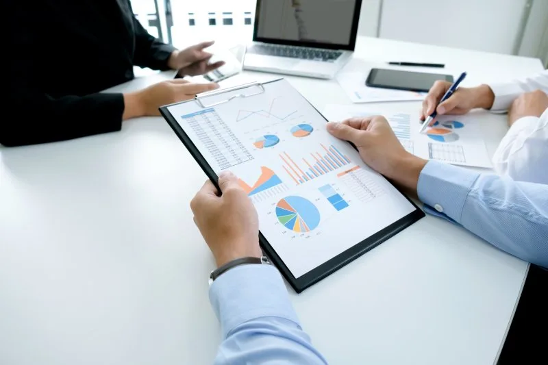Financial advisors reviewing performance charts and data during a client meeting. 